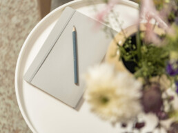 Unterlagen liegen auf einem Tisch mit Blumen in der Therapie Praxis von Eva Weinmann in Prien am Chiemsee.